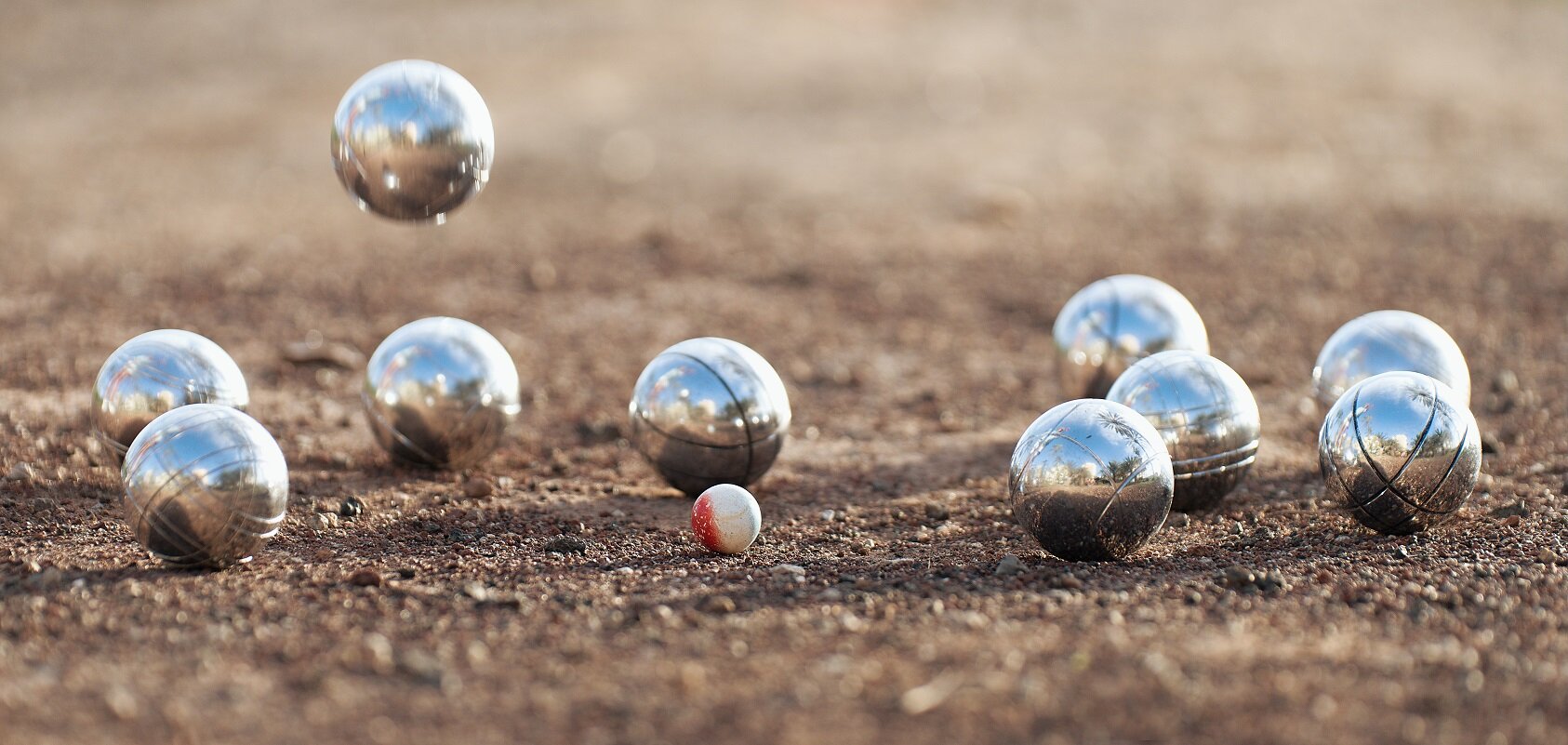 Bocciabahn mit startklaren Kugeln für das Spiel | © stock.adobe.com Bocciakugeln auf Sandbahn in Spielformation | © stock.adobe.com