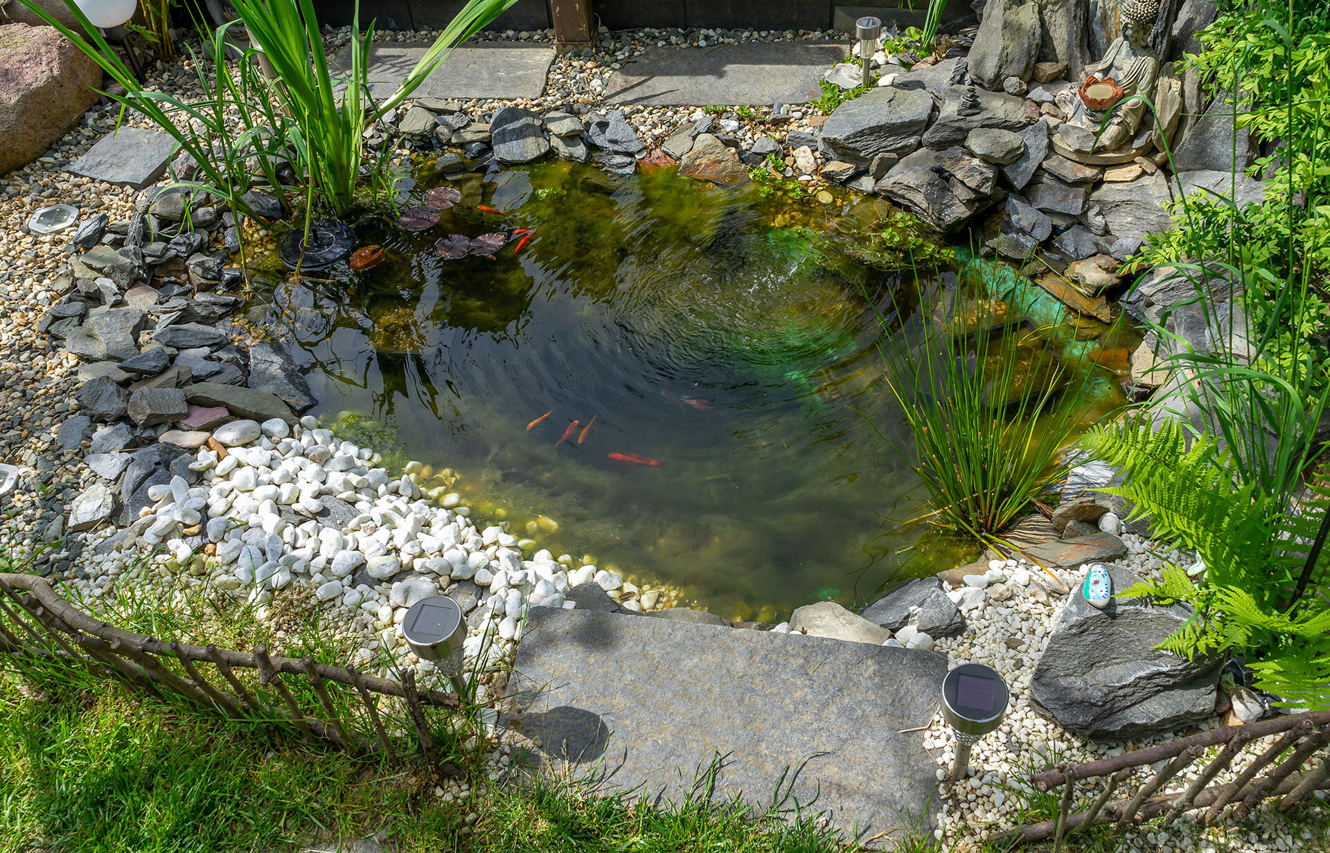Gartenteich mit Steinen, Wasserlauf und grüner Bepflanzung | © stock.adobe.com