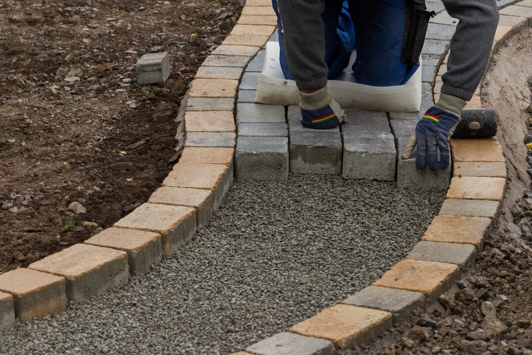 Anlage eines Gartenwegs Schritt für Schritt | © stock.adobe.com Pflastersteine werden mit Gummihammer im Weg verlegt | © stock.adobe.com