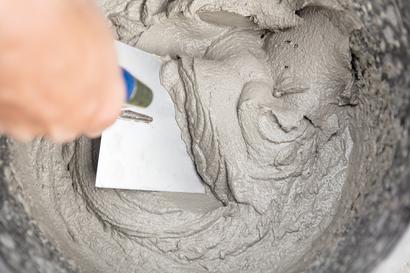 Verarbeitung von Magerbeton im handwerklichen Einsatz | © stock.adobe.com Spachtel verteilt Magerbeton in einem Eimer | © stock.adobe.com