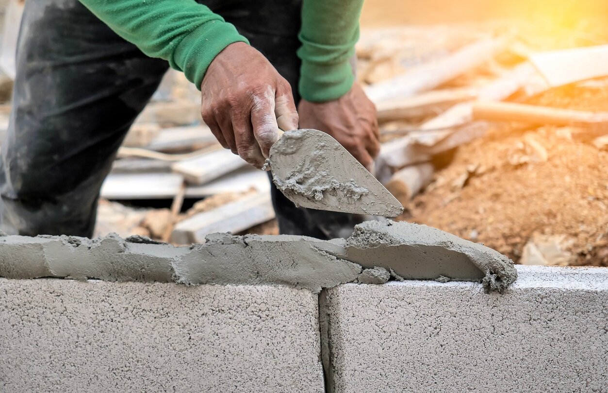 Betonverarbeitung beim Fundamentieren im Außenbereich | © stock.adobe.com Arbeiter schüttet Magerbeton in Holzverschalung | © stock.adobe.com