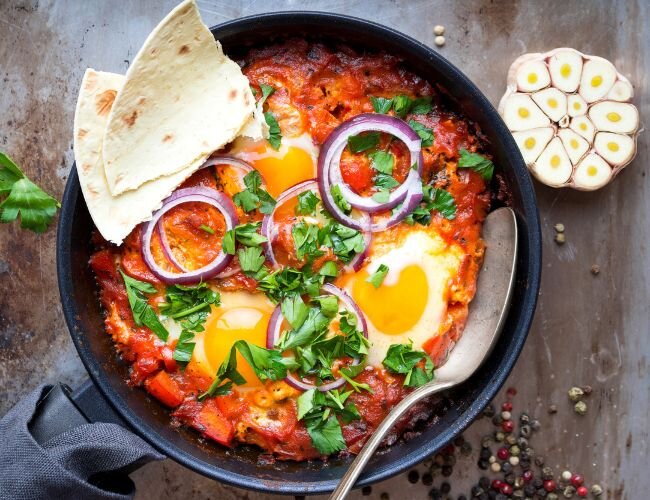 Shakshuka mit Tomaten, Eiern und Fladenbrot in Pfanne serviert | © stock.adobe.com