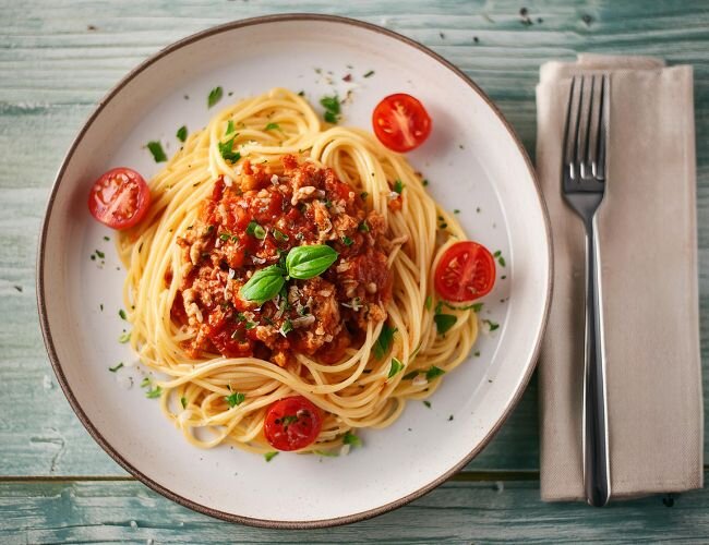 Spaghetti mit Tomatensauce und Basilikum auf weißem Teller | © stock.adobe.com