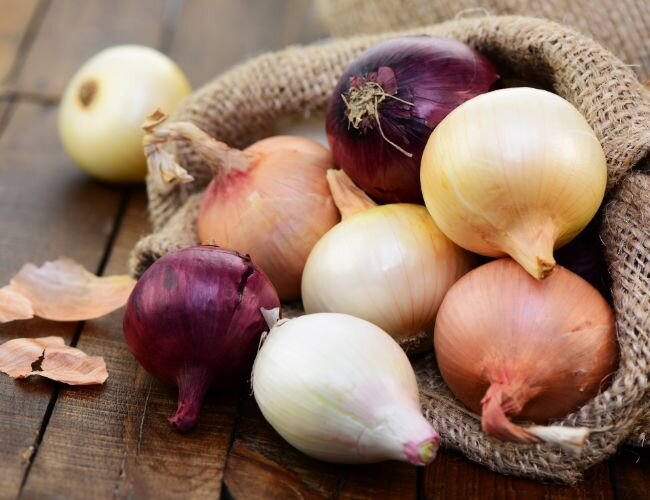 Verschiedene Zwiebelsorten auf Holzteller nebeneinander | © stock.adobe.com